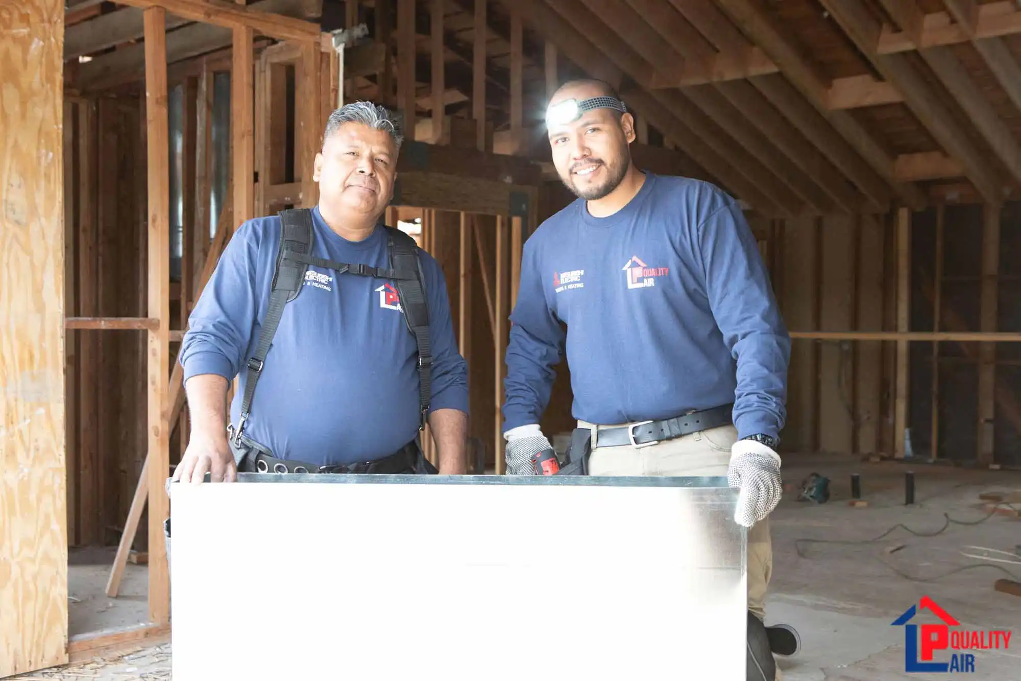 Two LP Quality technicians performing maintenance on an outdoor AC condenser unit.