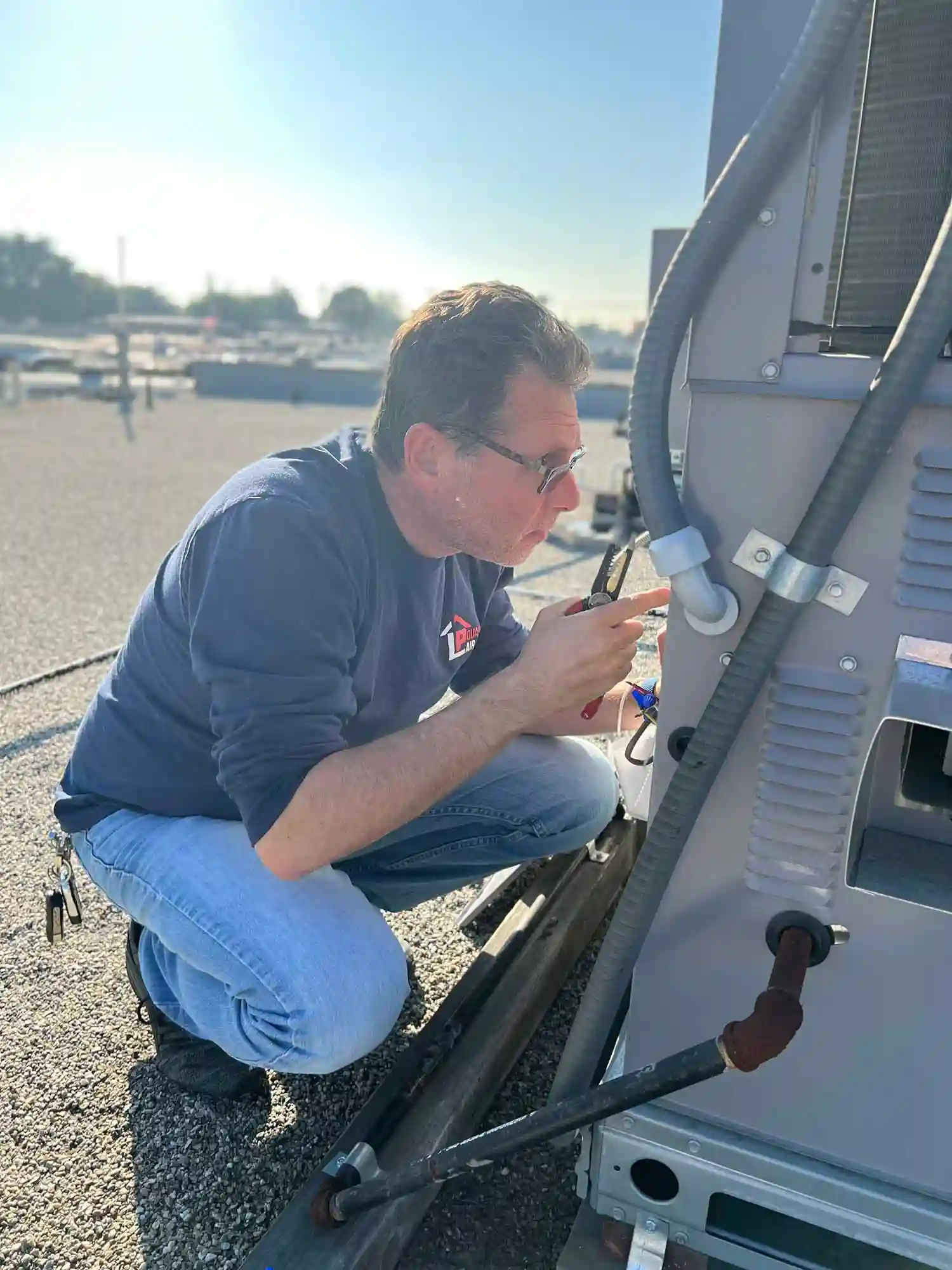 LP Quality technician inspecting and wiring a commercial rooftop HVAC unit.