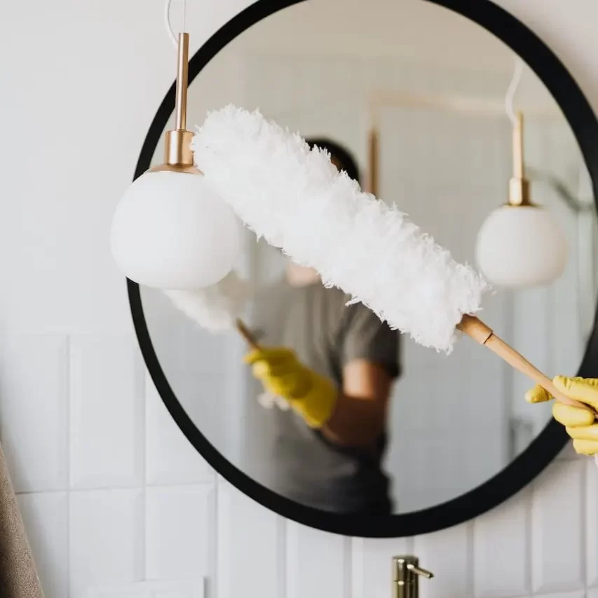 A person using a duster to clean household surfaces, highlighting the need to remove dust and indoor allergens.
